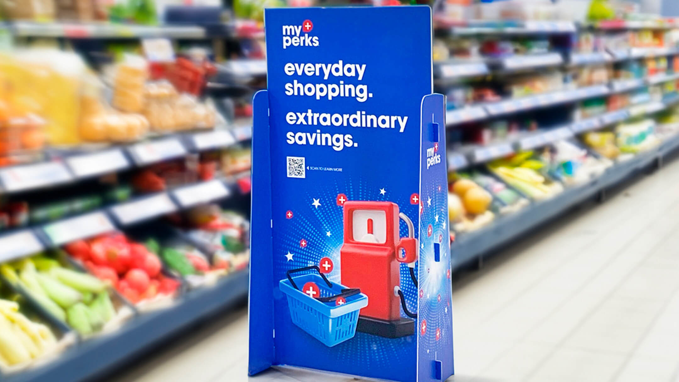 Freestanding blue promotional display for "myPerks" rewards program in a grocery aisle. Features slogans, a gas pump, and a shopping basket illustration.
