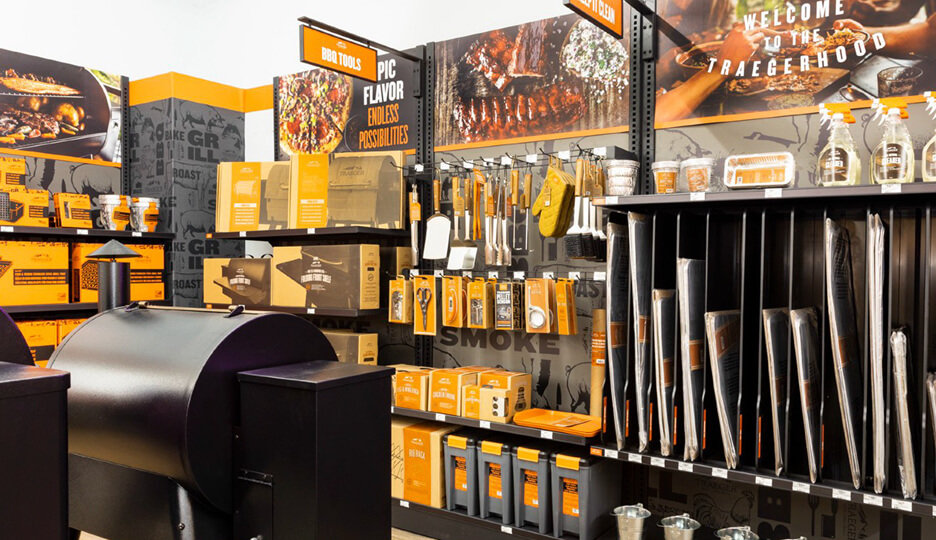 Traeger grill accessory wall with tools, liners, and cleaning supplies in a retail store setup.