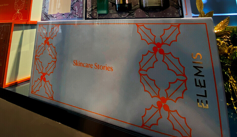 Close-up of an Elemis “Skincare Stories” gift box decorated with red holly motifs and branding.