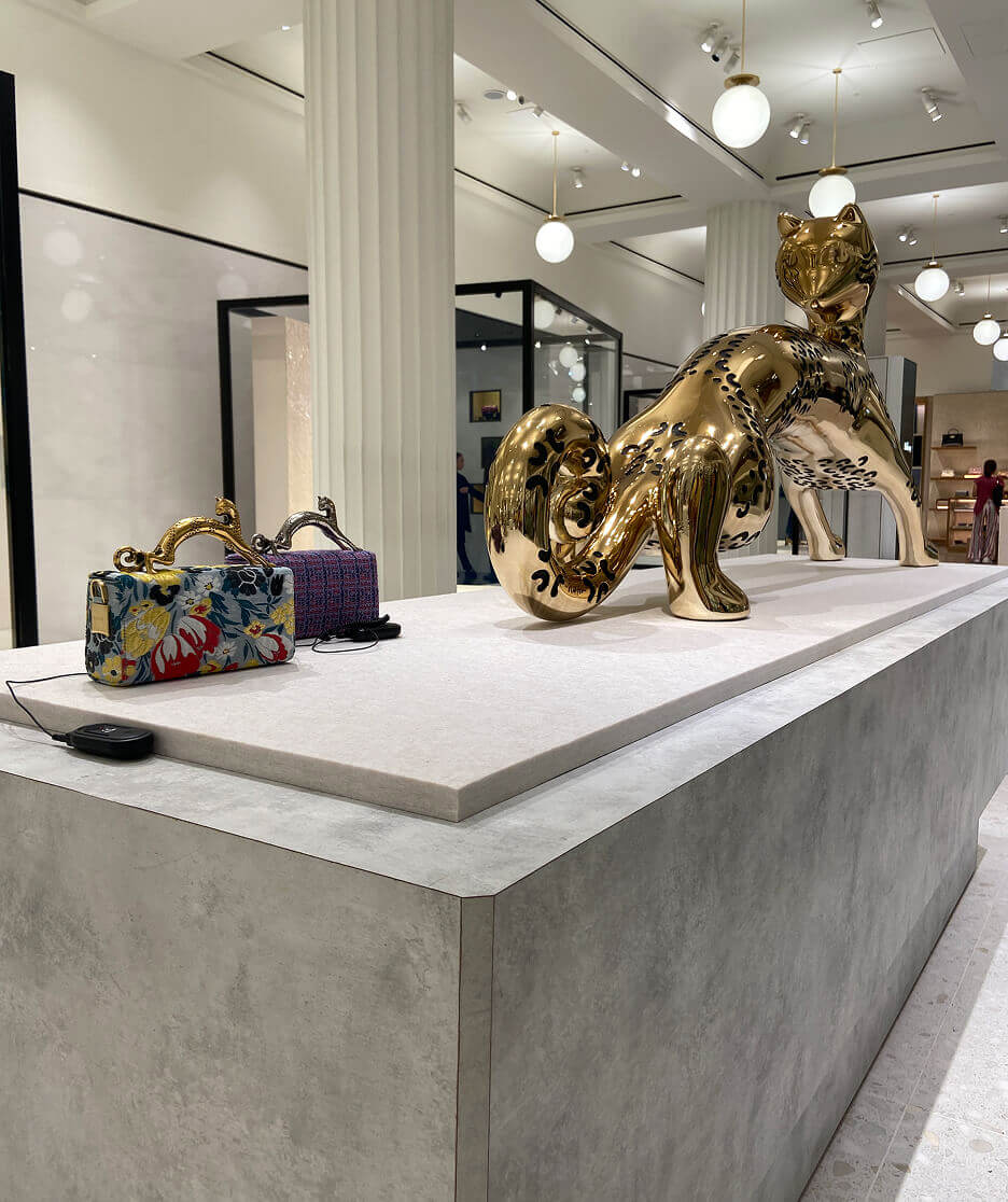 Interior of a Lanvin boutique featuring elegant archways, wood flooring, luxury dresses on display, designer handbags on glass shelves, and a central gold panther sculpture.